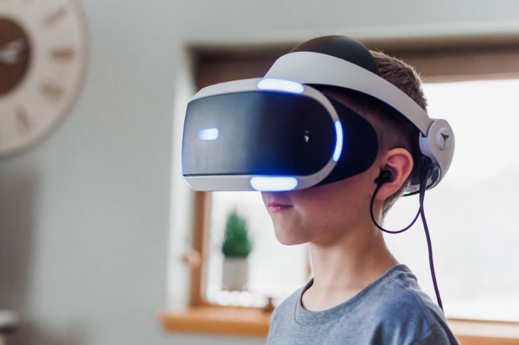 Playstation nelja virtuaalreaalsus prillid teismelise poisi peas.