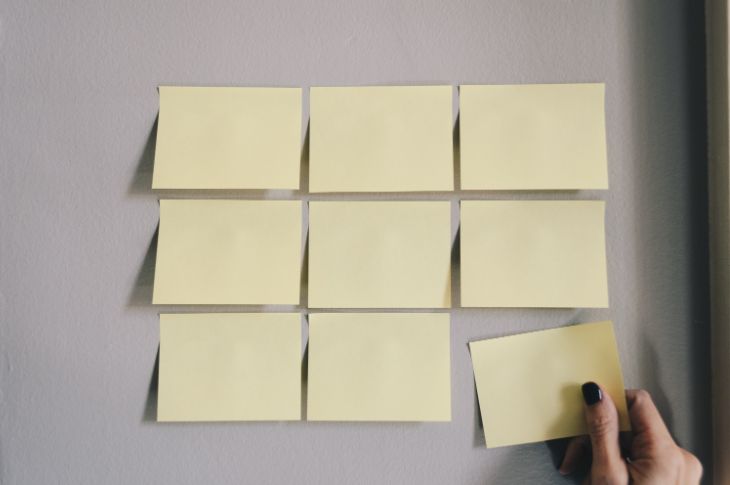 inimene paneb postit pabereid seinale
