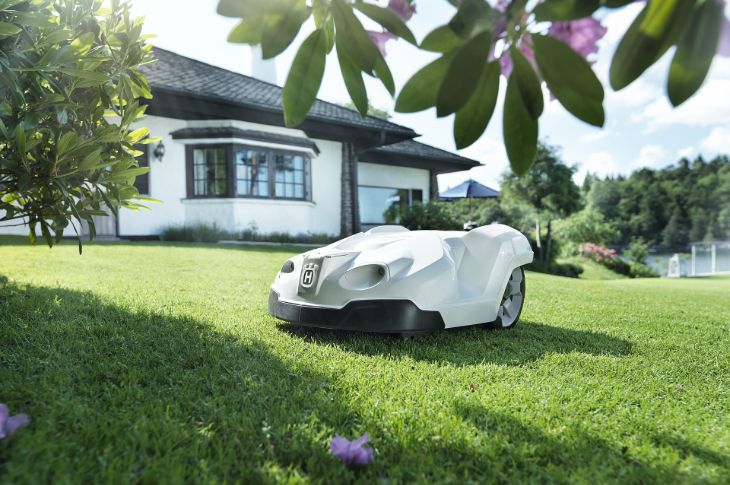 Valge fassaadiga maja taustal niidab muru valge Husqvarna robotniiduk.