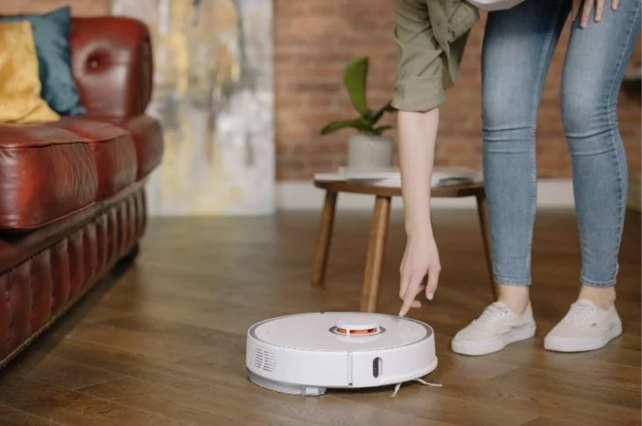 Sieviete slēdz iekšā robotu putekļu sūcēju